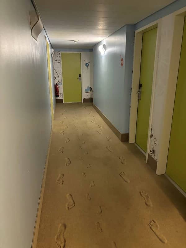 Hotel hallway carpet printed with sandy footprints leading past the room doors