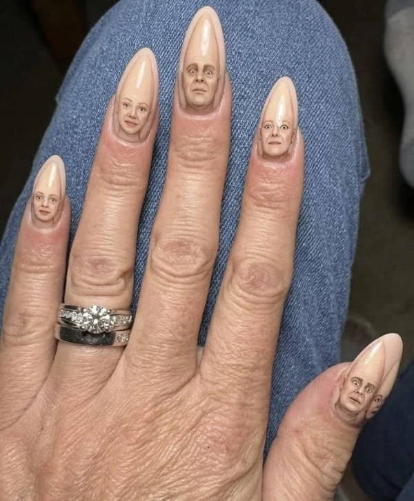 Manicure with long pointed nails painted with tiny faces of the Coneheads characters
