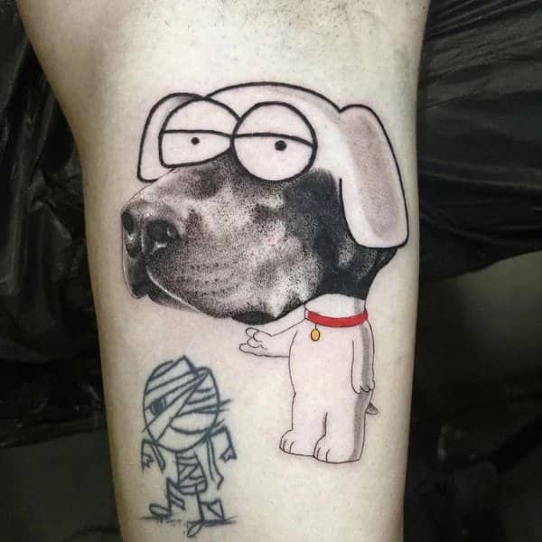 Tattoo of a cartoon dog body with a realistic black dog face, beside a mummy doodle
