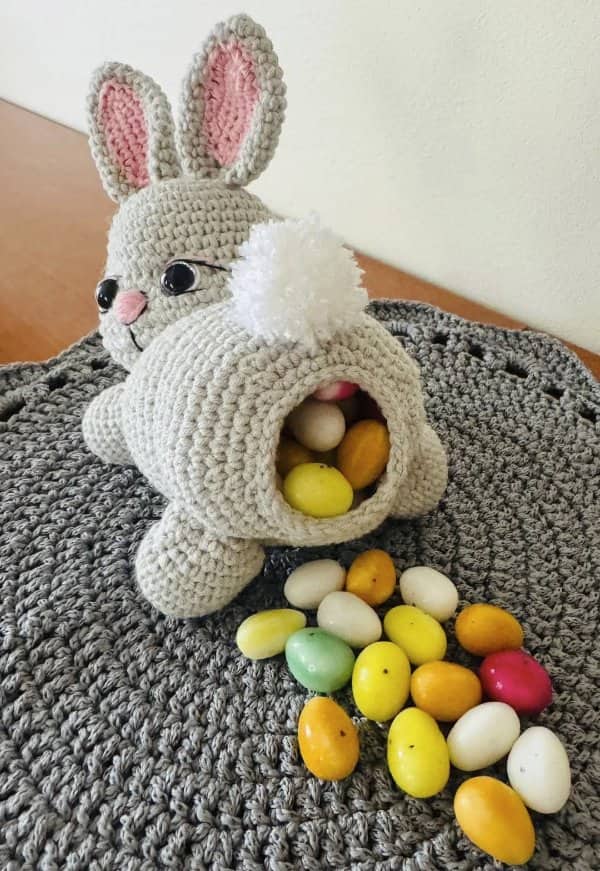 Crocheted bunny candy dispenser with colorful jelly eggs spilling out of its back end
