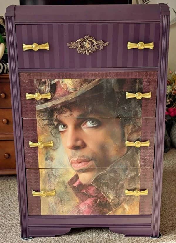 Purple dresser with a painted Prince portrait spread across its drawers and gold handles