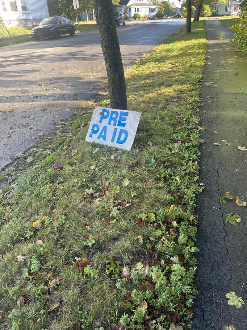 Yard sign on a grassy strip with blue letters spaced to read PRE PA ID