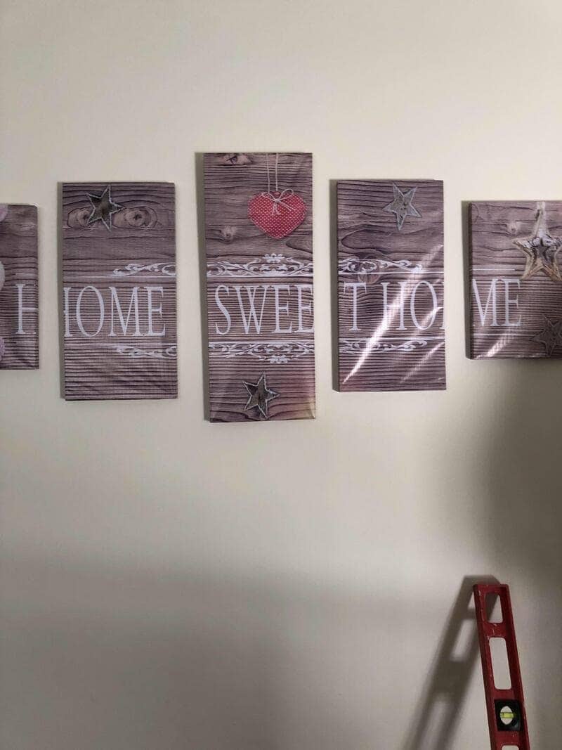 Wall canvas panels meant to say Home Sweet Home hung so the words break wrong