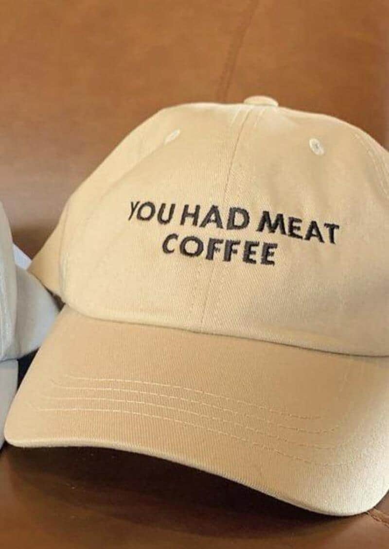 Beige cap embroidered with the phrase You had meat coffee in black letters