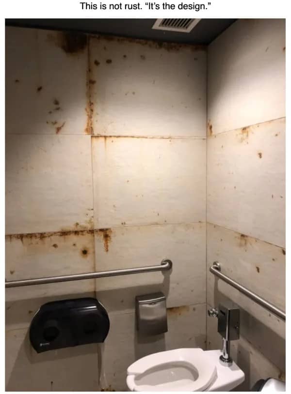 Public restroom with rust colored stains streaking the white walls, described as intentional design