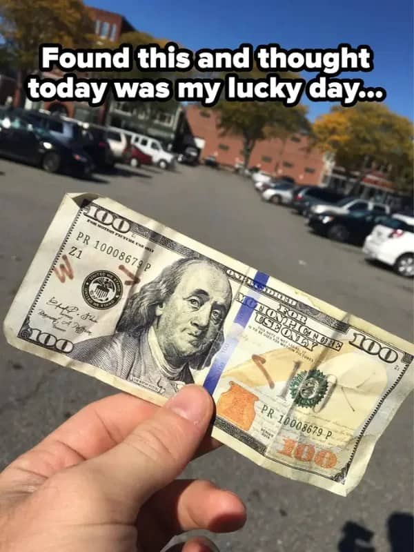 Hand holding a found 100 dollar bill marked for motion picture use only