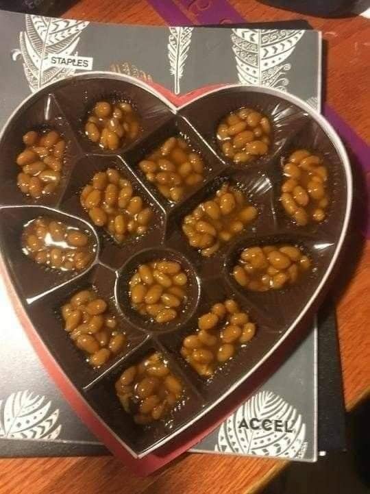 Heart-shaped Valentine's chocolate box with every slot filled with baked beans.
