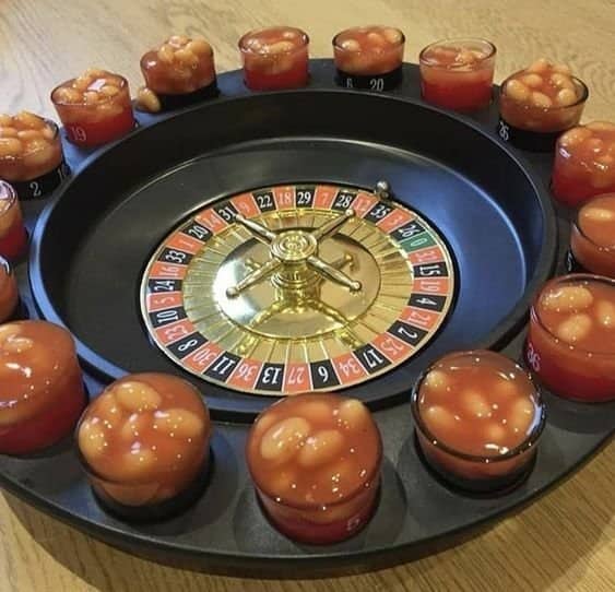 Drinking roulette wheel with every shot glass around the rim filled with baked beans.