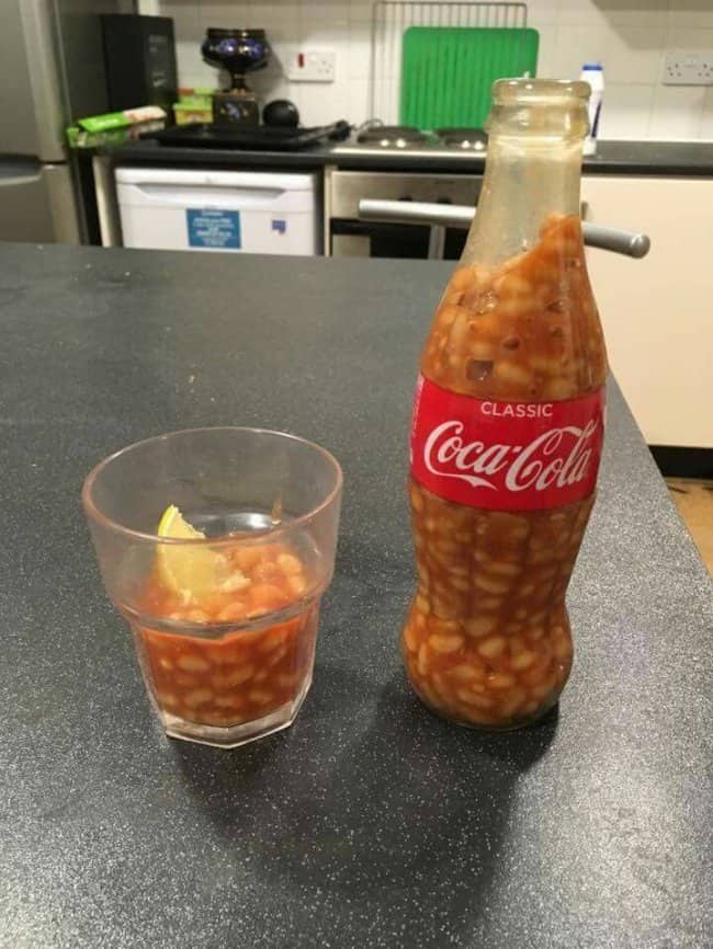 Coca-Cola glass bottle filled with baked beans beside a glass of beans with a lemon slice.