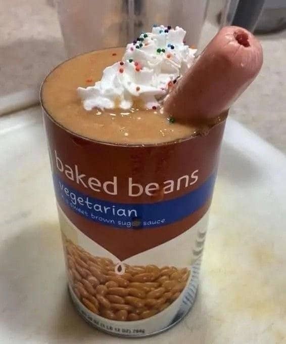 Can of vegetarian baked beans topped with whipped cream, sprinkles, and a hot dog sticking out.