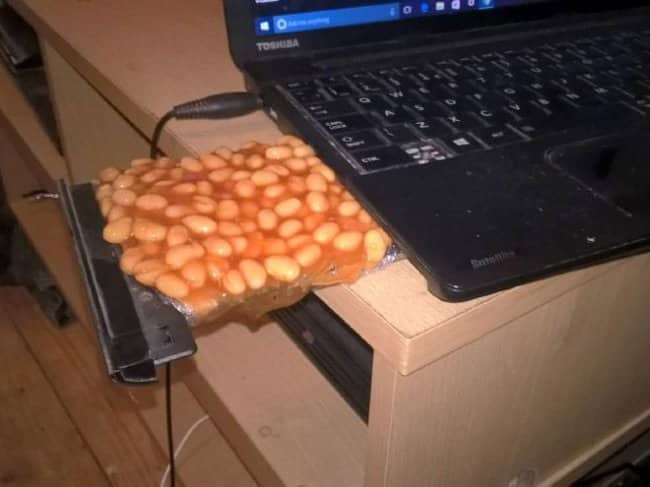 Laptop disc drive tray pulled out and covered with a flat slab of baked beans like a CD.