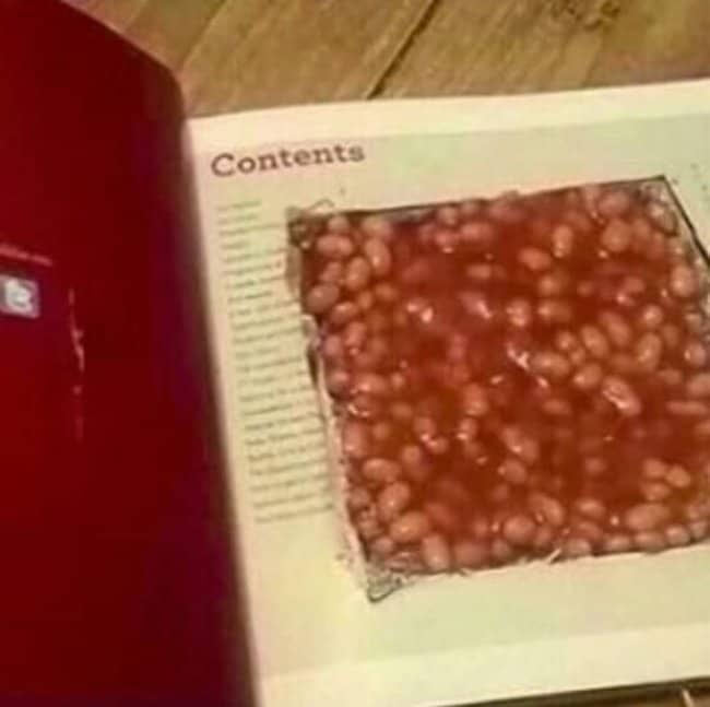 Hollow book opened to a contents page, with the cut-out compartment filled with baked beans.