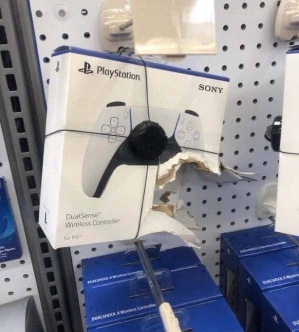 Game controller box with its plastic window ripped open hanging on a store shelf