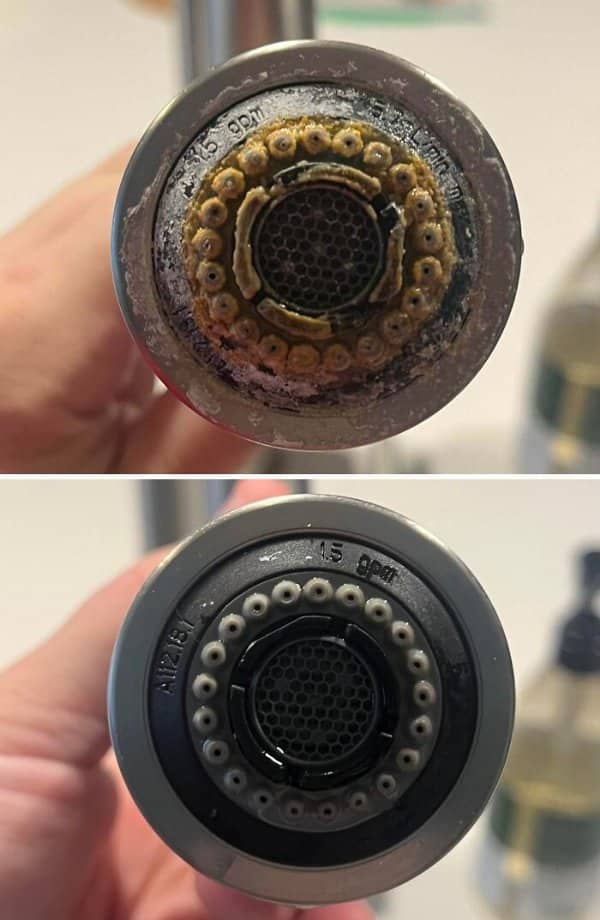 Kitchen faucet sprayer head crusted with yellow mineral buildup, cleaned back to gray nozzles.