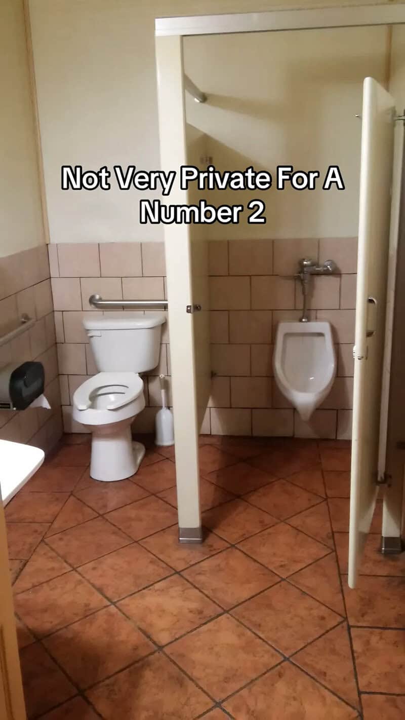 Construction fails example of a bathroom stall that also contains an open urinal beside the toilet.