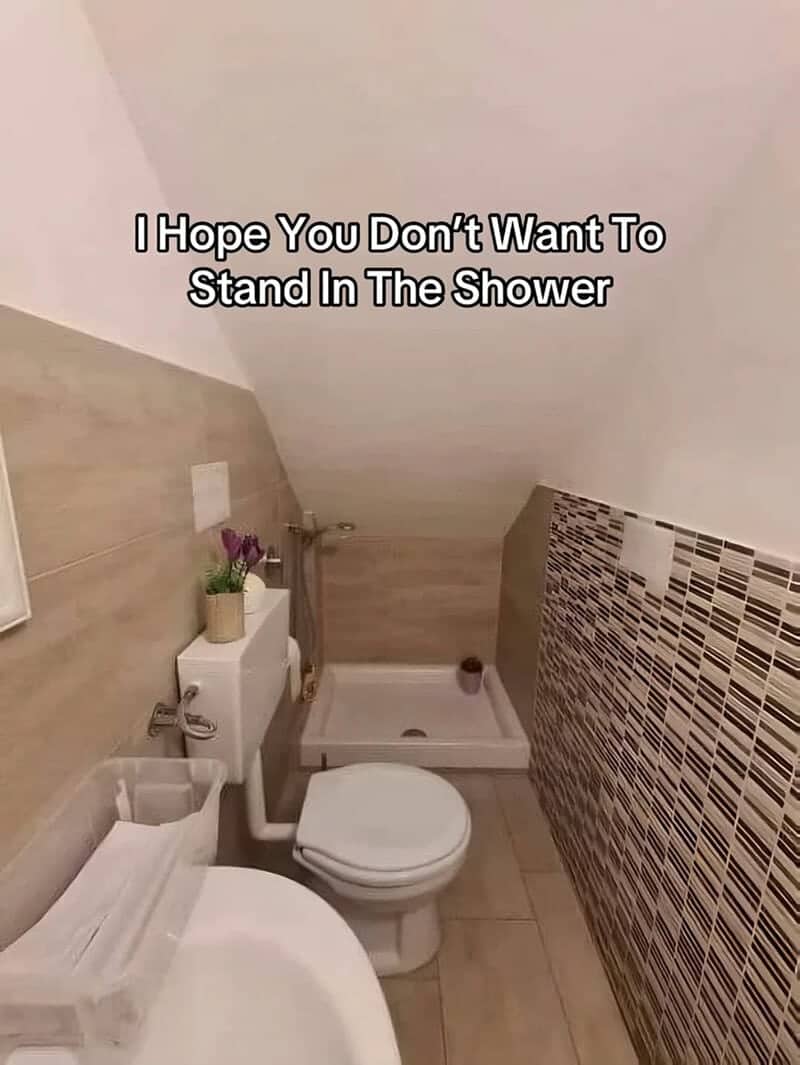 Tiny attic bathroom with a shower tray tucked under a steeply sloped low ceiling.