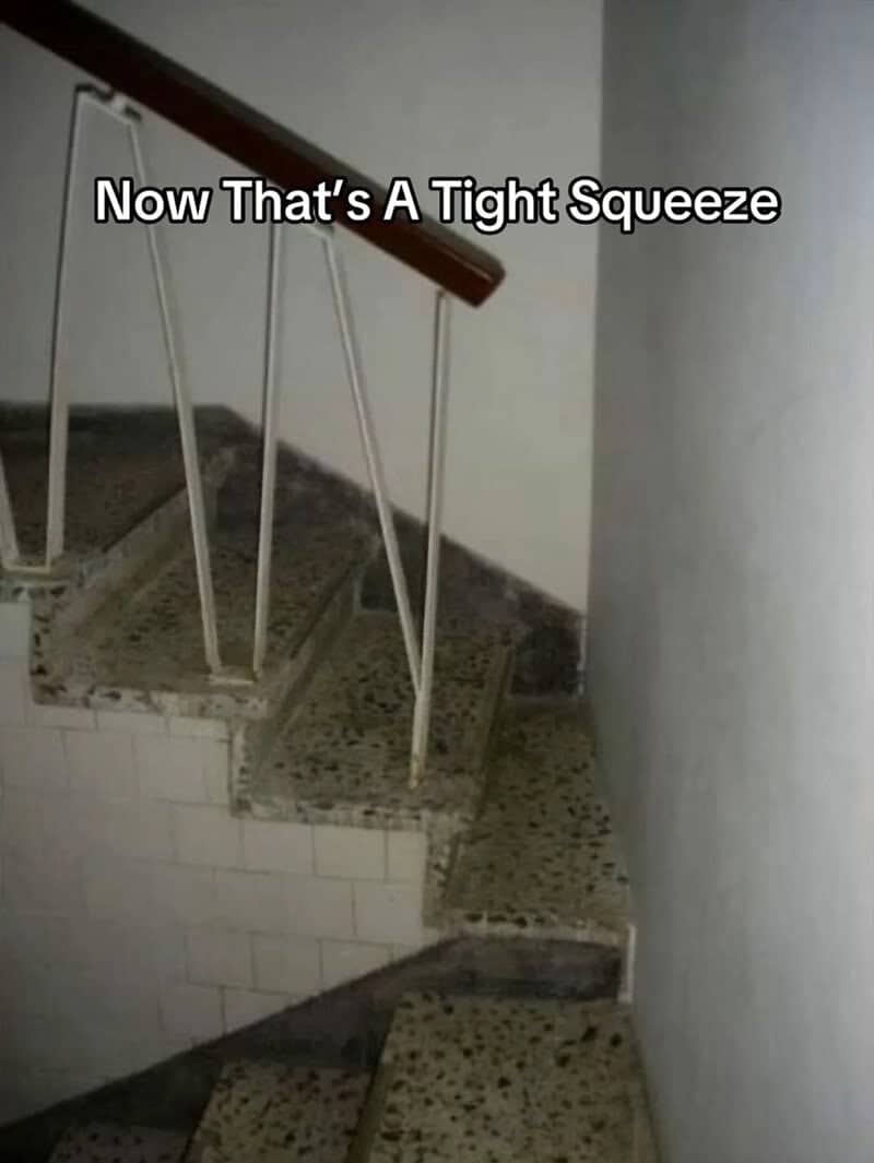Narrow terrazzo staircase that pinches into a tiny gap between the railing and the wall.