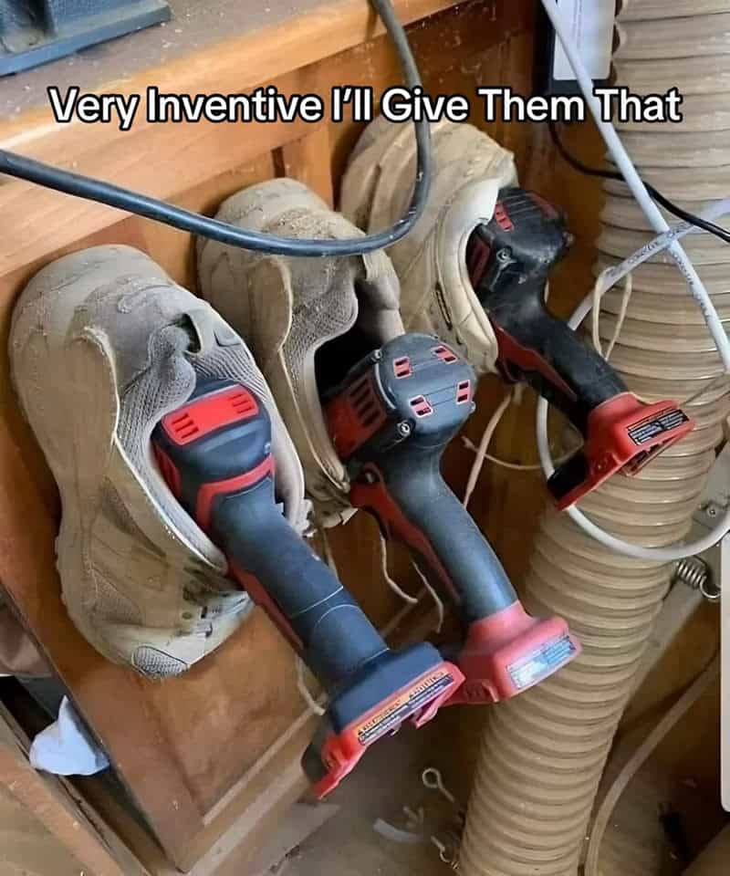 Cordless drills stored inside old dusty sneakers mounted on a workshop wall like holsters.