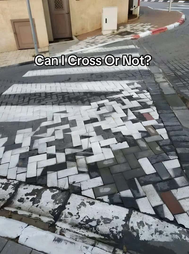 Crosswalk built from paving bricks laid in a scrambled pattern so the stripes barely exist.