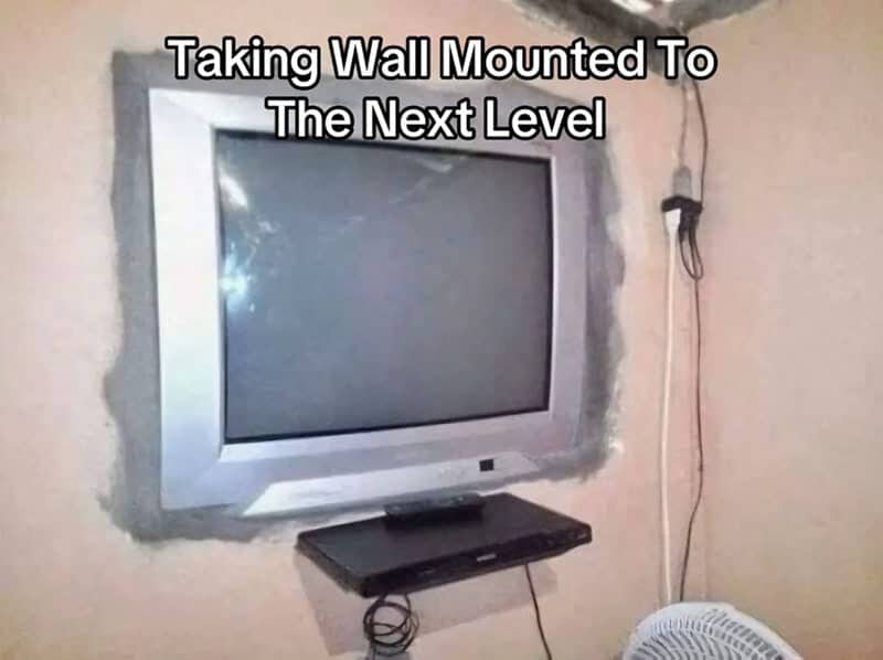 Old tube television set recessed into a rough hole cut into a bedroom wall.