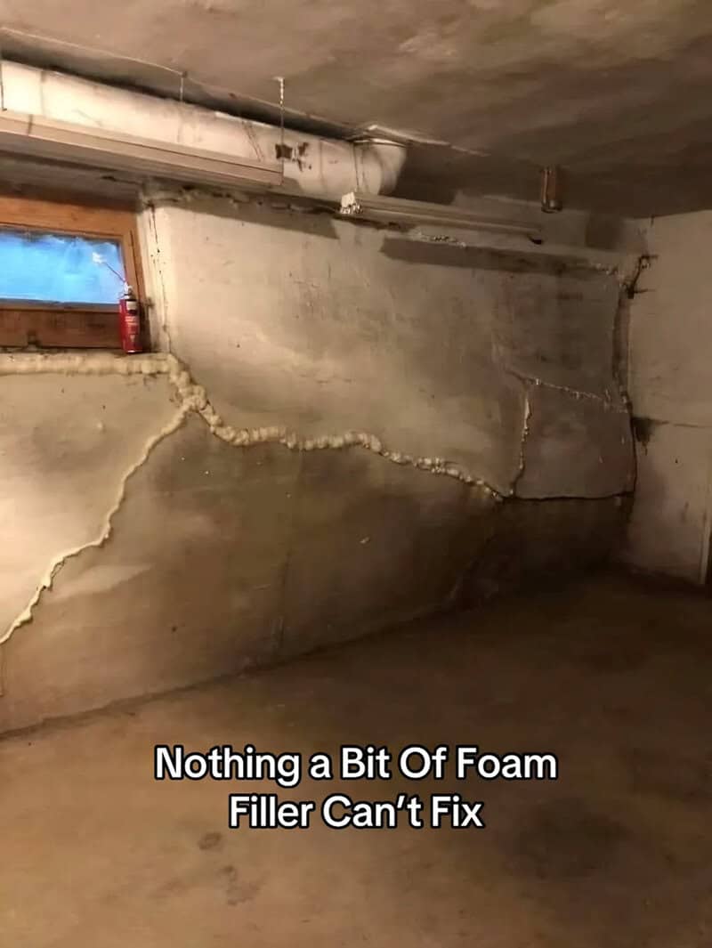 Basement wall with large structural cracks filled in with spray foam instead of real repairs.