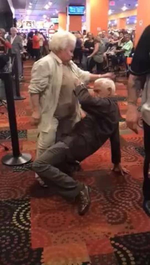 Older couple dancing with a dramatic dip on a casino floor as onlookers watch.