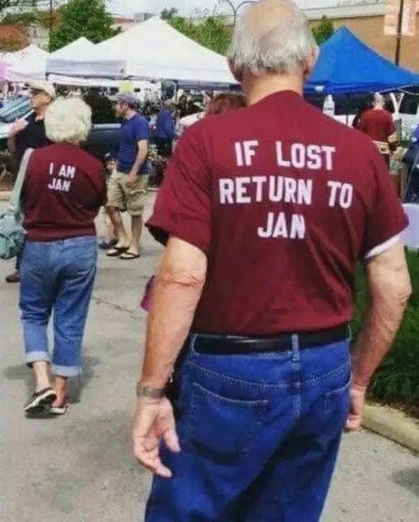 Older couple at a market wearing matching shirts reading I Am Jan and If Lost Return to Jan.