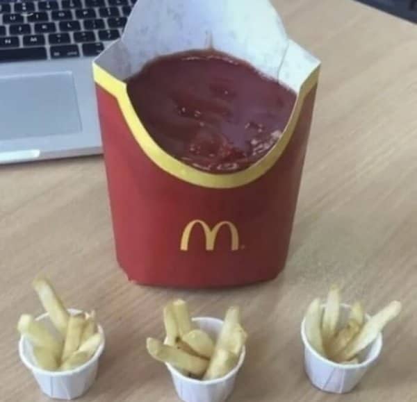 McDonald's fry container filled with ketchup while the fries sit in small paper cups.