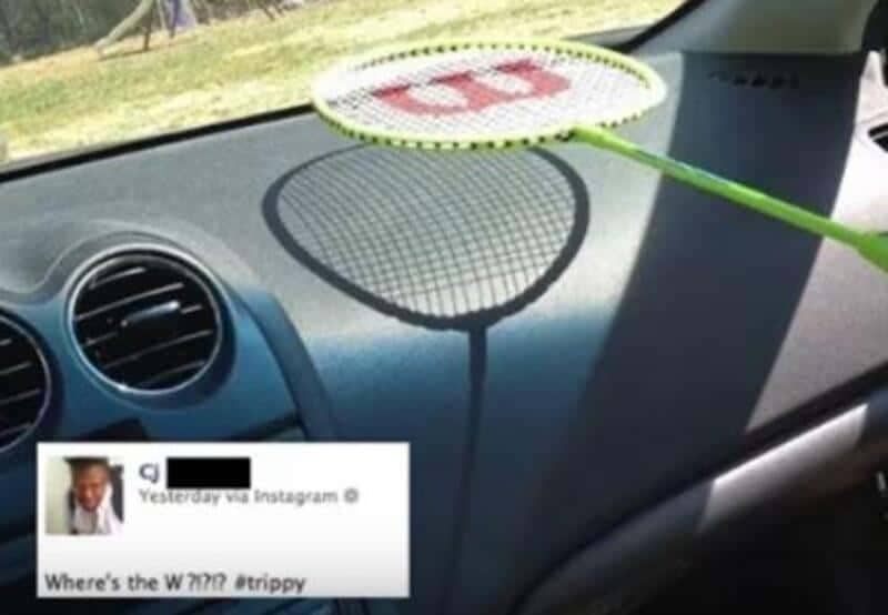 Badminton racket on a car dashboard casting a shadow, with a caption asking where the W went.