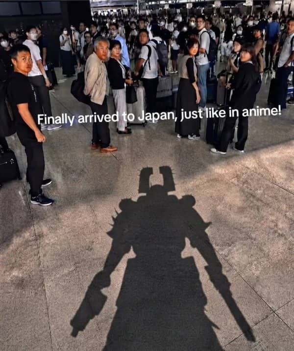 Shadow of a giant robot cast across a crowded Japanese train station, captioned just like anime.
