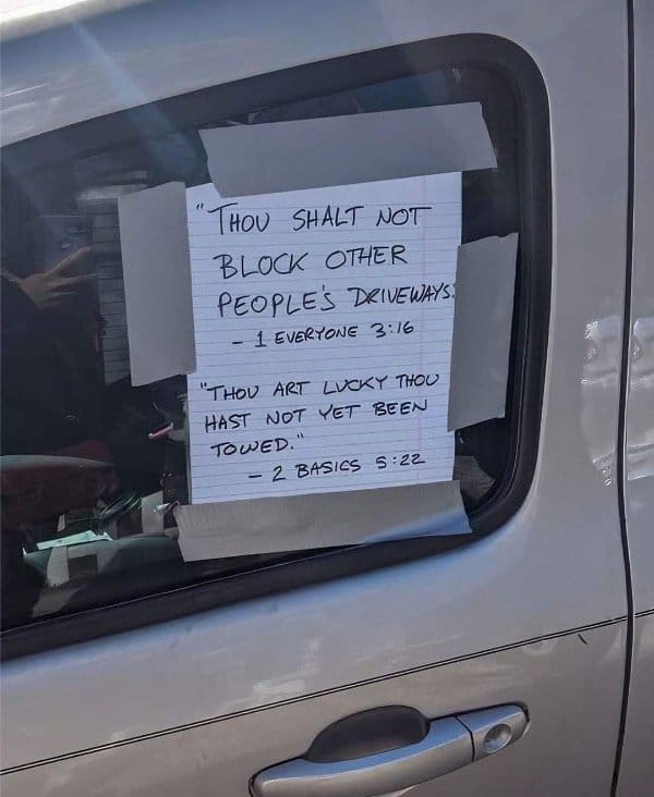 Lined paper taped to a van window quoting fake scripture about not blocking driveways.