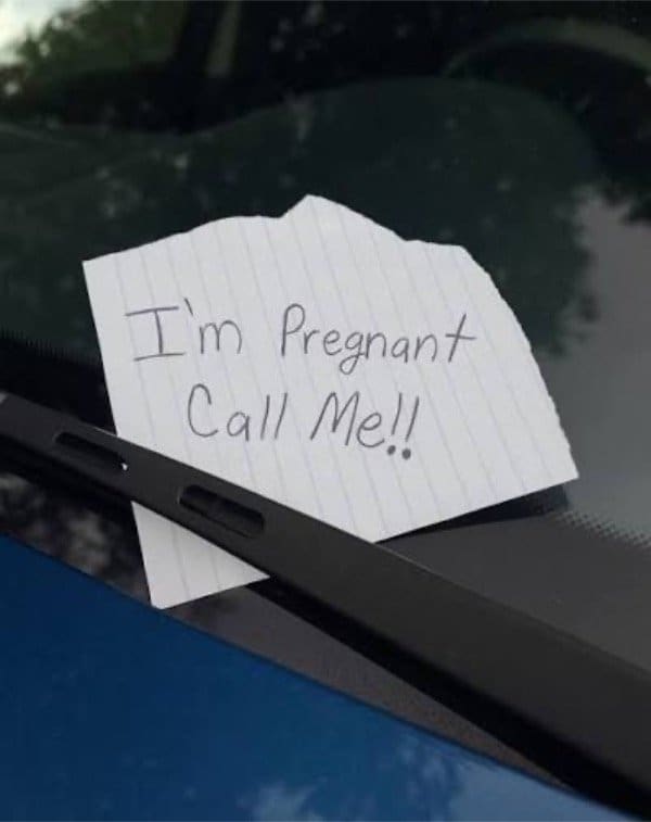 Torn note under a windshield wiper reading I'm pregnant, call me.