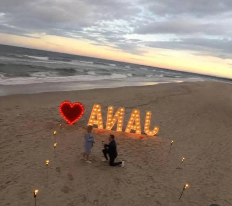 Meme dump beach proposal photo where the light-up letters read badly from the camera angle