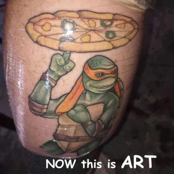 Tattoo of Michelangelo the Ninja Turtle spinning a pizza on one finger, labeled now this is art