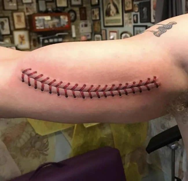 Arm tattoo designed to look like the red stitching on a baseball across the bicep