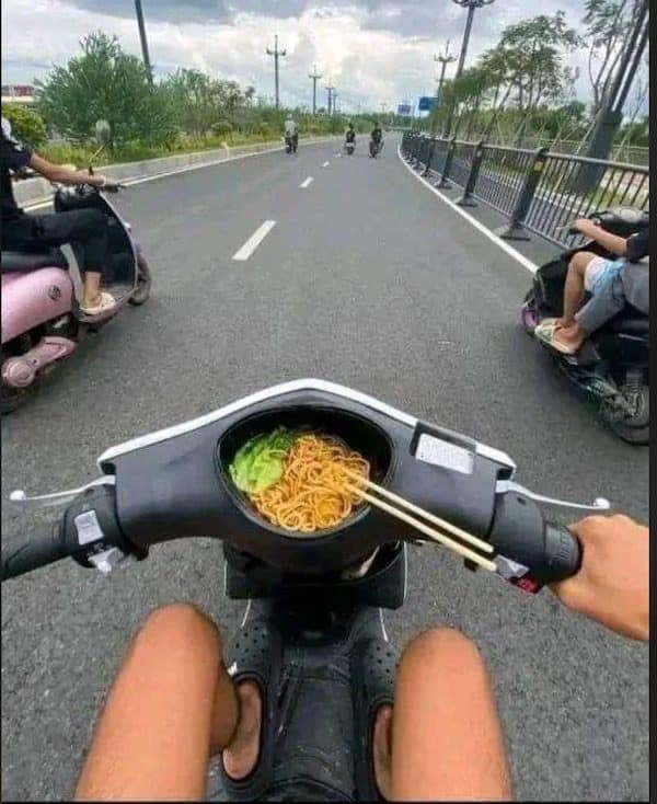 Scooter rider's view of noodles and chopsticks in a bowl built into the dash, meme dump commute