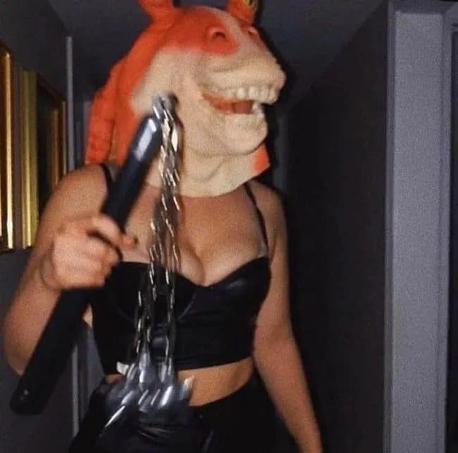 Partygoer in a Jar Jar Binks mask and black outfit swinging a spiked toy flail.