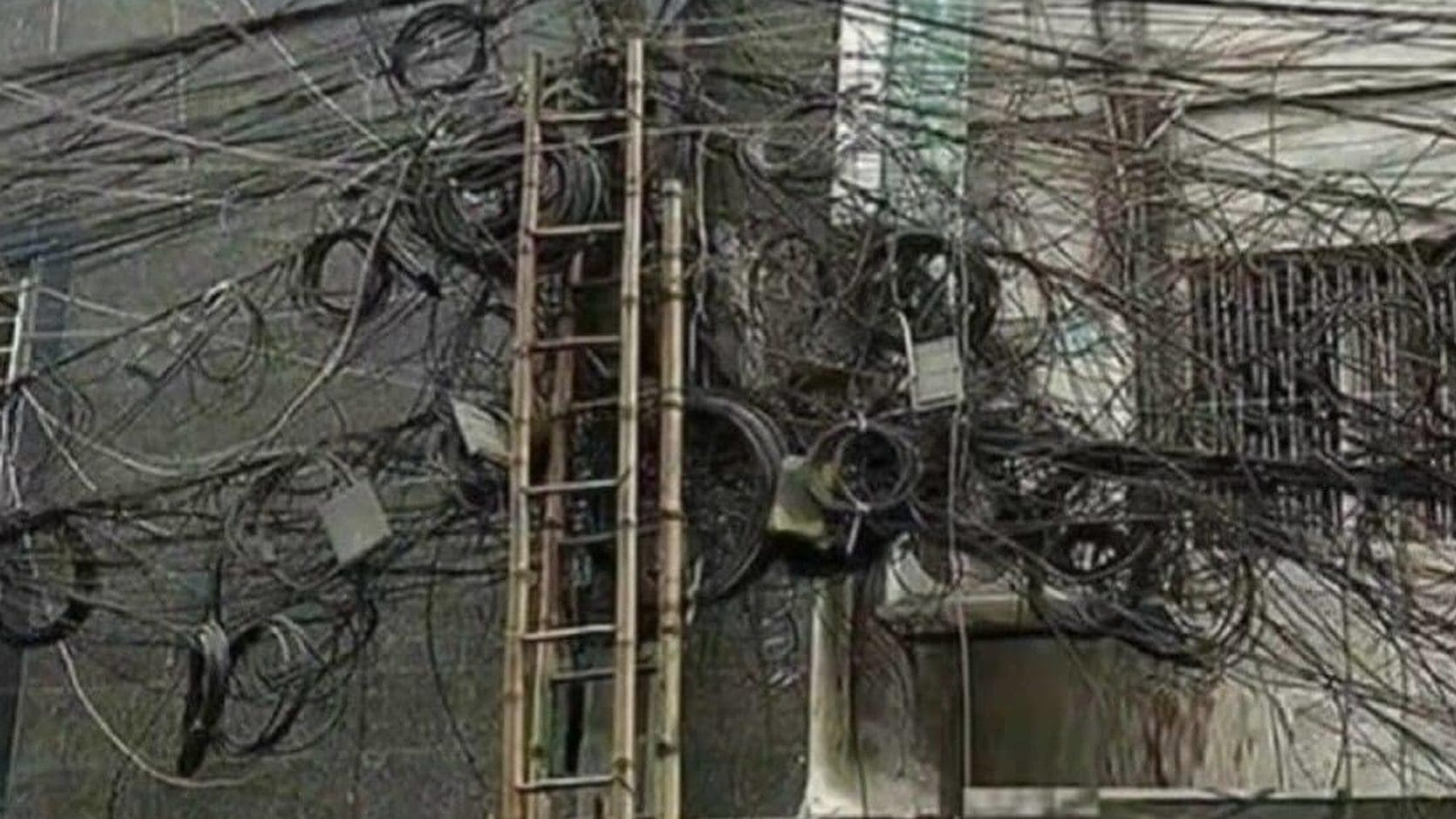 A building wall buried under a hopeless knot of tangled cables and a ladder, the meme dump answer to how life is going.