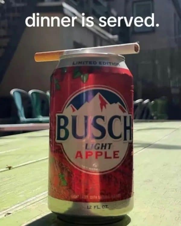 A meme dump dinner: a Busch Light Apple can with a cigarette balanced on top.