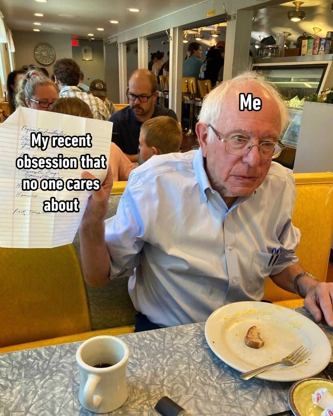 Bernie Sanders at a diner holding notes labeled an obsession no one cares about