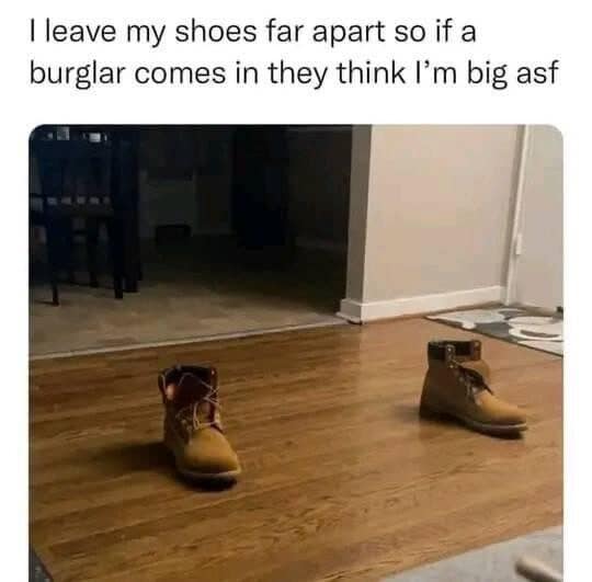 Two tan work boots set far apart on a wood floor to scare burglars.