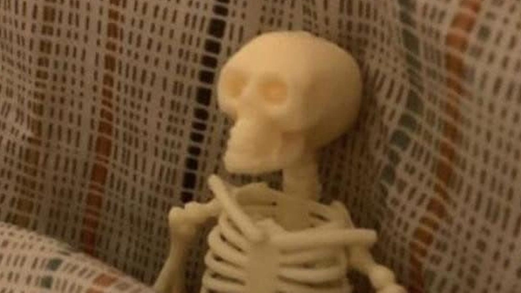 Small toy skeleton tucked under plaid bed covers like it has been waiting up for weeks, the featured pick from today's meme dump.
