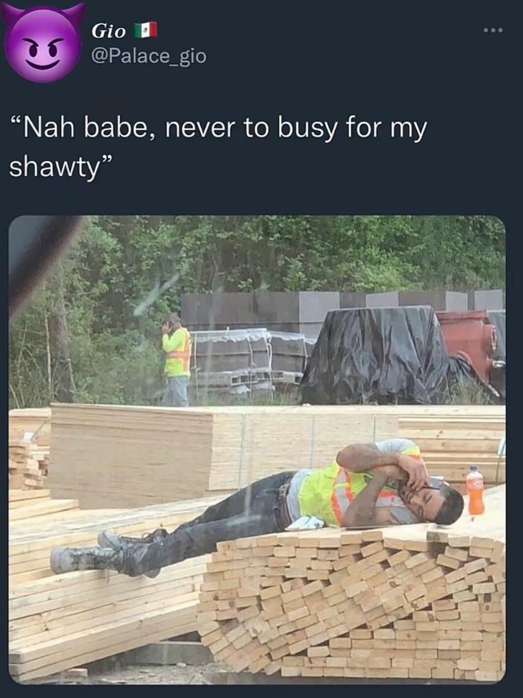Construction worker lounges on a lumber stack taking a phone call, captioned never too busy for his girl.