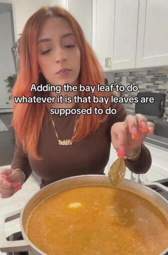Woman dropping a bay leaf into a pot of soup without knowing what it does.