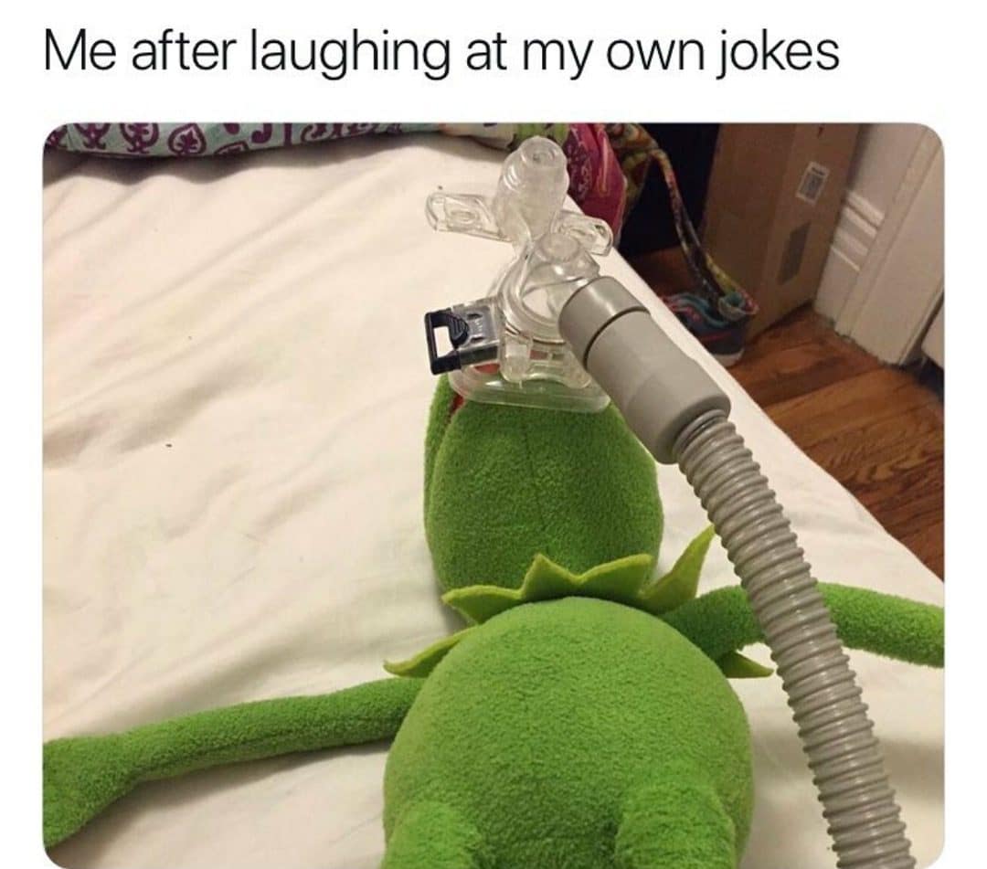 Kermit the Frog lying face down on a bed wearing a CPAP mask after laughing