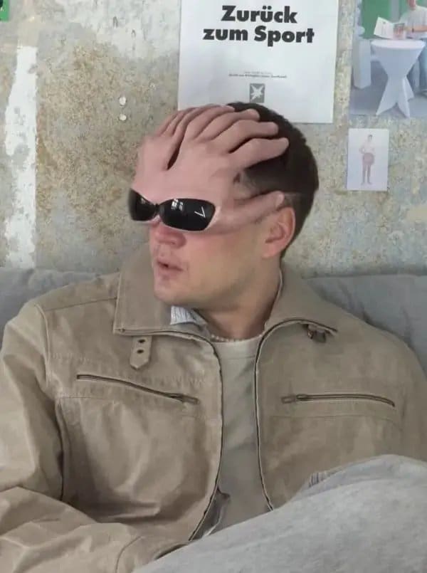 Man with someone's hand and sunglasses placed over his face, creating a baffling optical illusion.