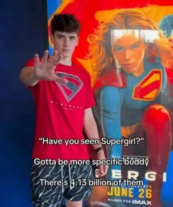 Guy beside a Supergirl poster joking that there are 4.13 billion super girls.