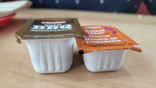 Two dipping sauce cups in shrinkflation examples where the newer cup sits noticeably shorter.