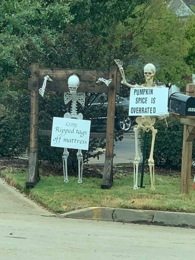 Skeleton in stocks for ripping mattress tags beside one holding a pumpkin spice sign.