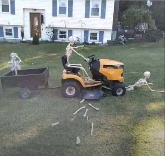 Skeleton on a riding mower pulling a cart while another lies in pieces behind it.